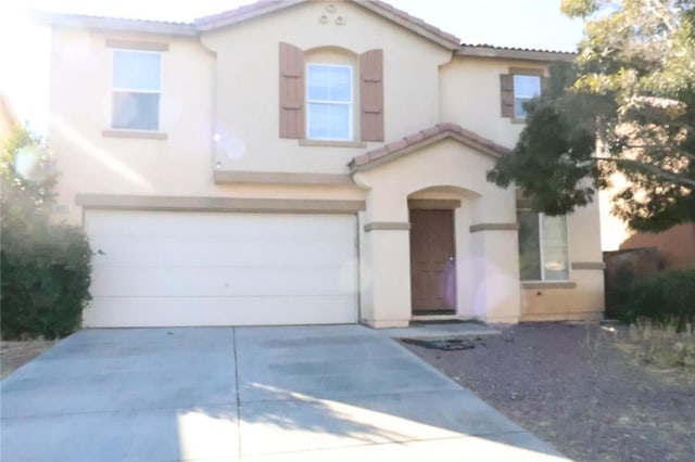 mediterranean / spanish house with an attached garage, a tiled roof, concrete driveway, and stucco siding