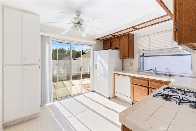 kitchen featuring sink, white appliances, tile counters, and ceiling fan