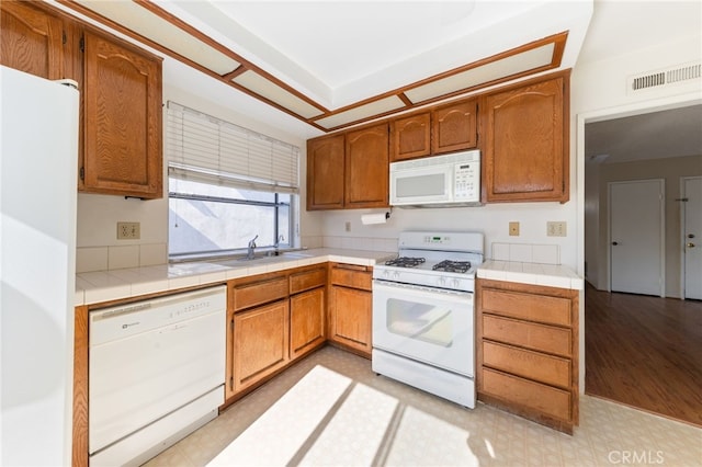 kitchen with tile countertops, light wood-type flooring, white appliances, and sink