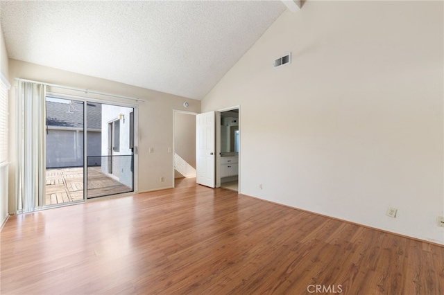 unfurnished room featuring high vaulted ceiling, a textured ceiling, and hardwood / wood-style flooring