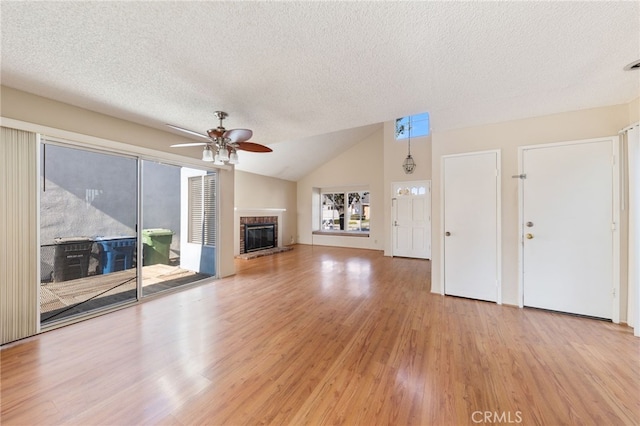 unfurnished living room with a textured ceiling, ceiling fan, light hardwood / wood-style flooring, a fireplace, and lofted ceiling