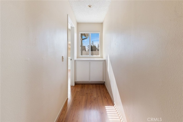 hallway with hardwood / wood-style floors and a textured ceiling