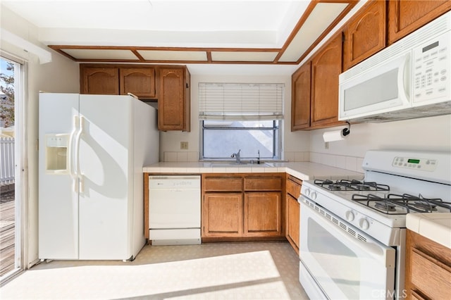 kitchen with tile countertops, white appliances, and sink