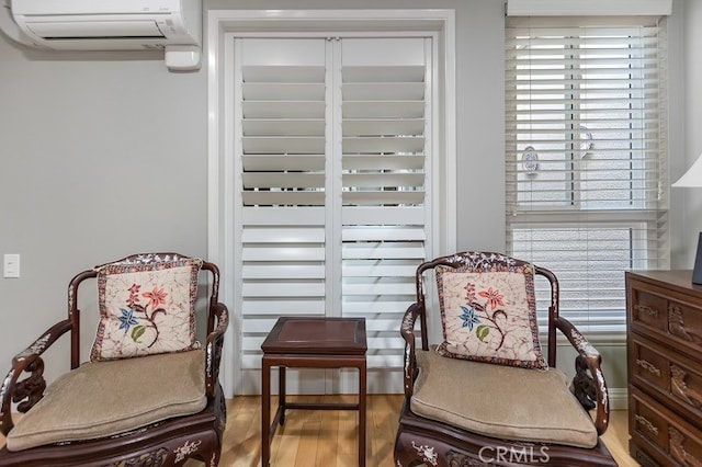 living area with hardwood / wood-style flooring and a wall mounted AC