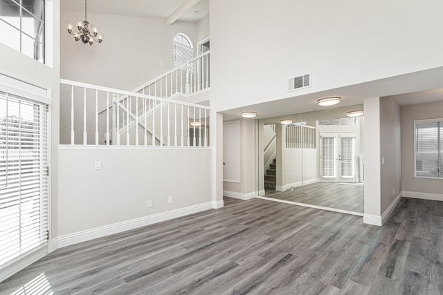 empty room featuring a wealth of natural light, dark hardwood / wood-style flooring, and a high ceiling