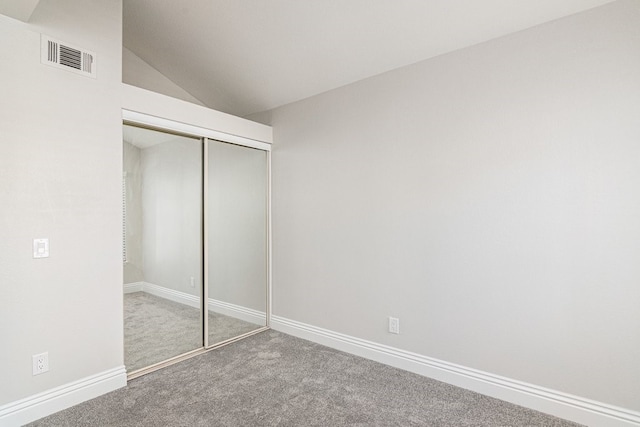 unfurnished bedroom featuring carpet flooring, a closet, and lofted ceiling