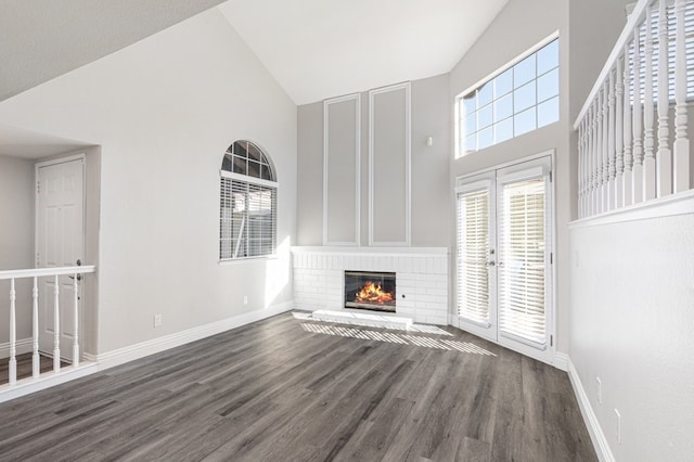 unfurnished living room featuring a fireplace, high vaulted ceiling, dark wood-type flooring, and french doors