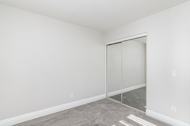 unfurnished bedroom featuring a closet and dark colored carpet