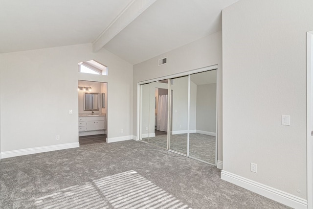 unfurnished bedroom with carpet, ensuite bathroom, sink, lofted ceiling with beams, and a closet