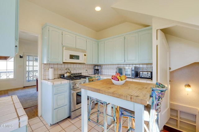 kitchen with backsplash, stainless steel range, tile countertops, and light tile patterned floors