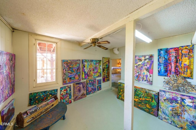 playroom featuring a textured ceiling, ceiling fan, and concrete floors