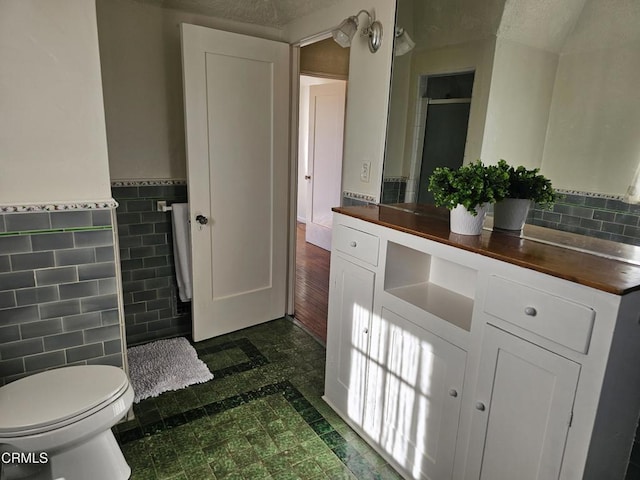 bathroom with vanity, tile walls, a textured ceiling, and toilet