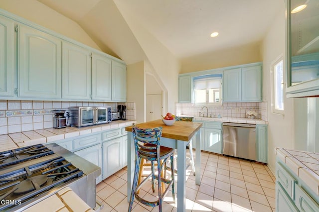 kitchen with stainless steel appliances, tile countertops, light tile patterned floors, and backsplash