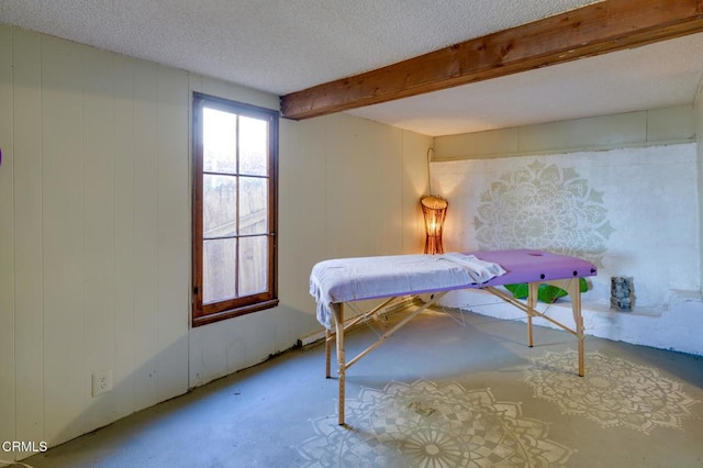 bedroom featuring a textured ceiling and wood walls