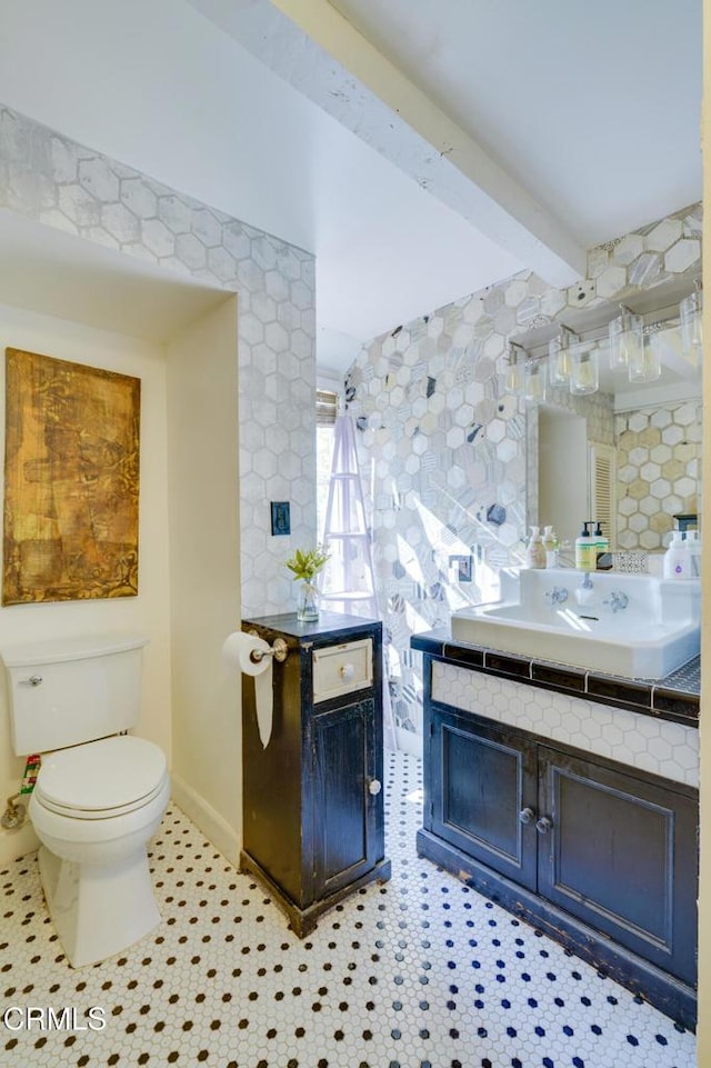 bathroom featuring vanity, tile patterned flooring, toilet, and beamed ceiling