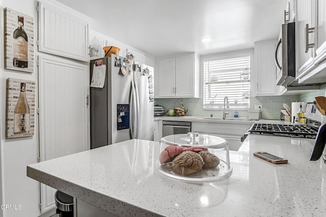 kitchen featuring decorative backsplash, stainless steel appliances, white cabinetry, and sink