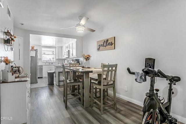 dining area featuring dark hardwood / wood-style flooring, ceiling fan, and sink