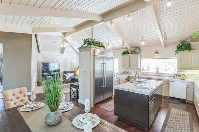 kitchen with dark hardwood / wood-style flooring, backsplash, built in refrigerator, white dishwasher, and a kitchen island