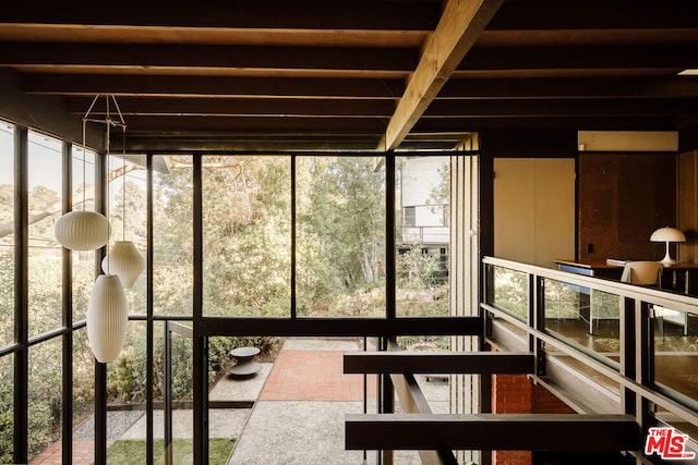 unfurnished sunroom with beam ceiling