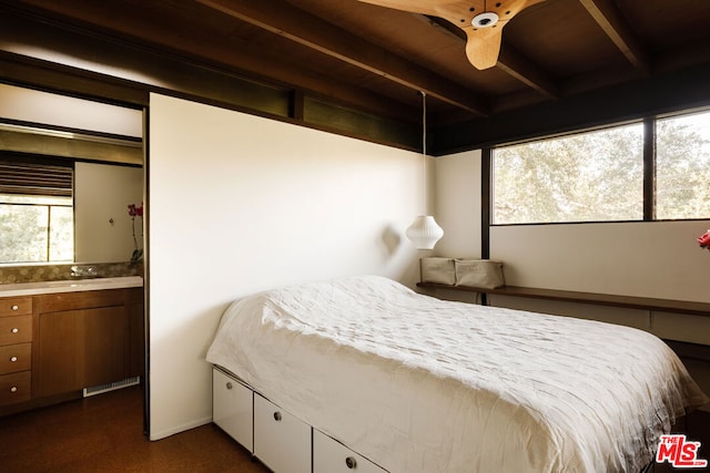 bedroom featuring beamed ceiling, ensuite bathroom, and ceiling fan