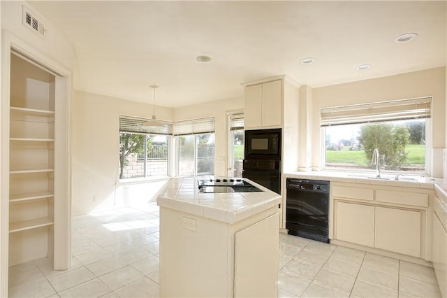 kitchen featuring black appliances, sink, decorative light fixtures, tile counters, and a kitchen island