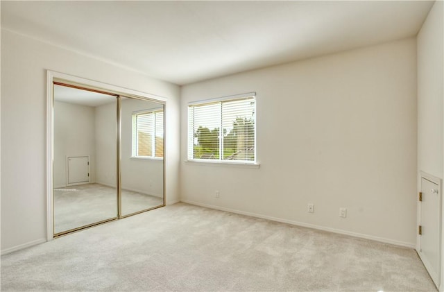 unfurnished bedroom with light carpet and a closet