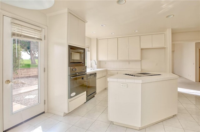 kitchen with tile countertops, white cabinets, decorative backsplash, a kitchen island, and stainless steel appliances