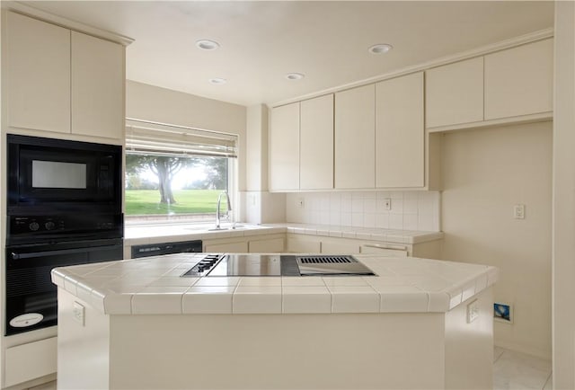 kitchen with a kitchen island, tile counters, black appliances, and sink