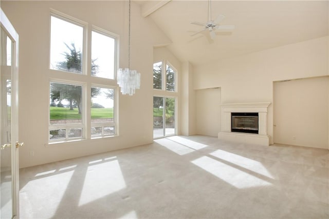 unfurnished living room with light carpet, beam ceiling, ceiling fan with notable chandelier, and high vaulted ceiling