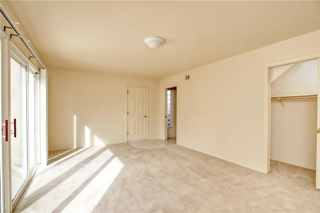 unfurnished bedroom featuring light carpet, a spacious closet, and a closet