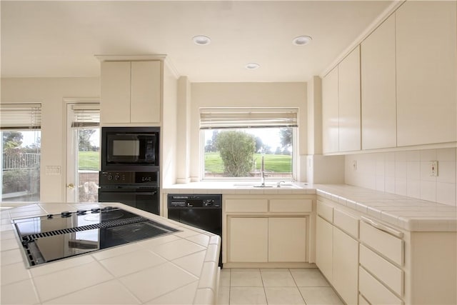 kitchen featuring tasteful backsplash, tile countertops, sink, and black appliances