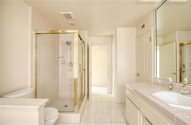 bathroom featuring tile patterned floors, vanity, toilet, and a shower with shower door