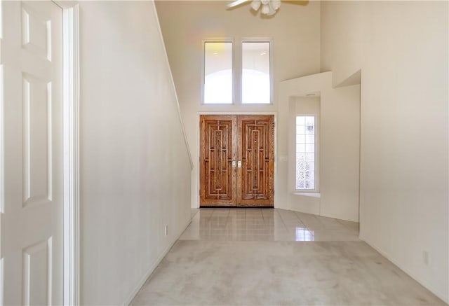 carpeted foyer featuring ceiling fan and a high ceiling