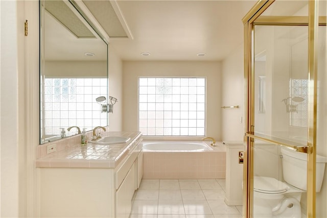 bathroom with tile patterned floors, vanity, tiled bath, and toilet