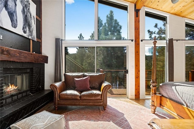 sunroom with plenty of natural light, wooden ceiling, vaulted ceiling, and a brick fireplace