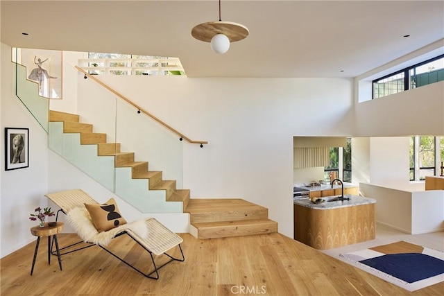 stairs with wood-type flooring, a wealth of natural light, a high ceiling, and sink