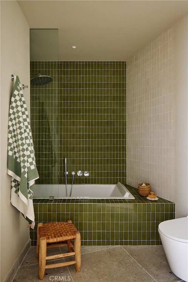 bathroom featuring a relaxing tiled tub, tile walls, and toilet