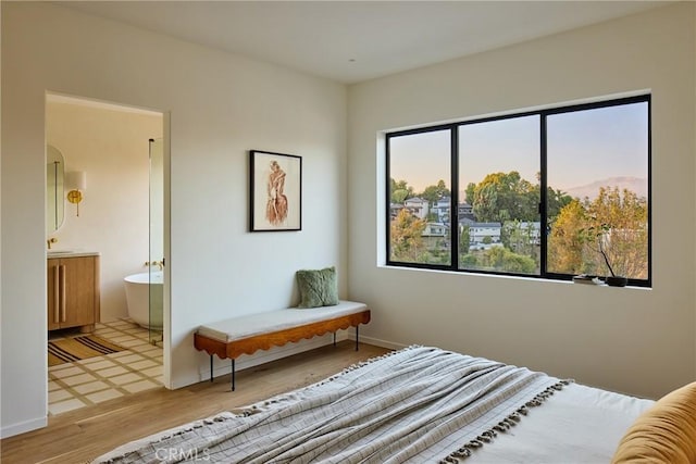 bedroom featuring light wood-type flooring and connected bathroom