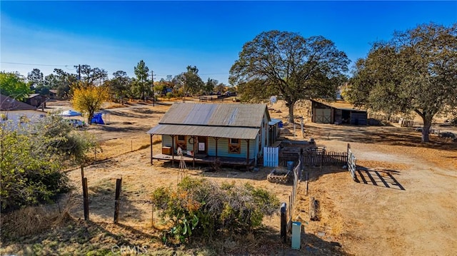 back of property featuring a porch, an outbuilding, and a rural view