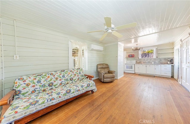 living room with a wall unit AC, wood walls, light hardwood / wood-style flooring, and ceiling fan