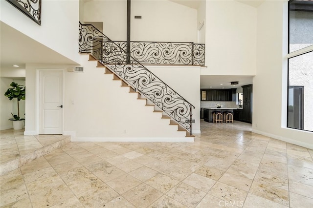 stairs featuring a towering ceiling, visible vents, and baseboards