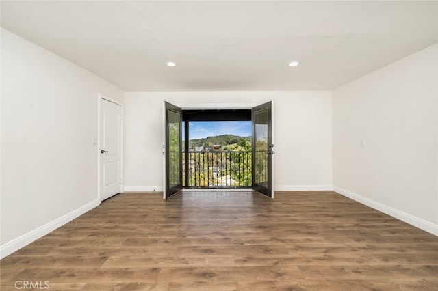 unfurnished room featuring baseboards, wood finished floors, and recessed lighting