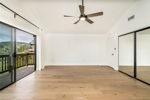 unfurnished bedroom featuring light wood-style flooring, visible vents, baseboards, vaulted ceiling, and access to exterior