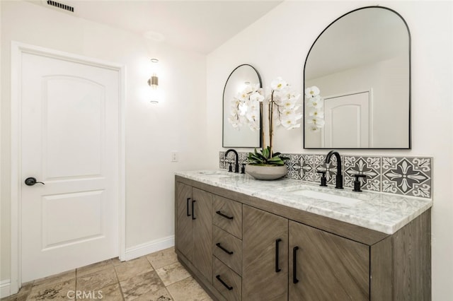 full bath with double vanity, a sink, visible vents, and baseboards