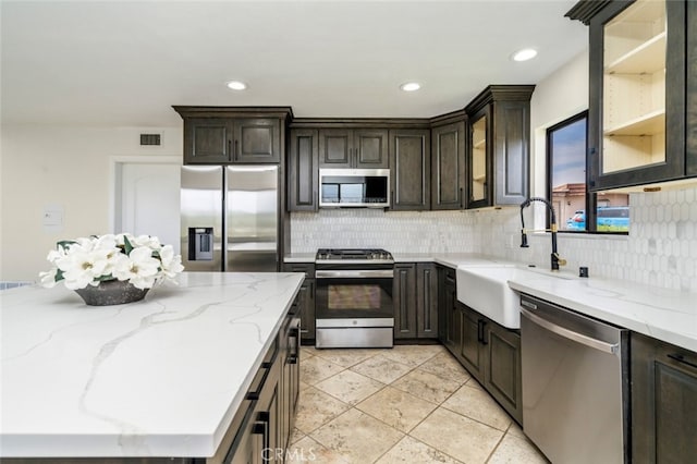 kitchen with visible vents, backsplash, appliances with stainless steel finishes, a sink, and dark brown cabinets