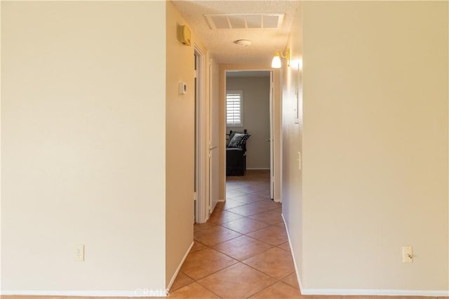 hall featuring light tile patterned flooring and a textured ceiling