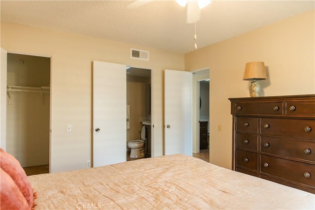 bedroom with a textured ceiling, ceiling fan, ensuite bathroom, and a closet