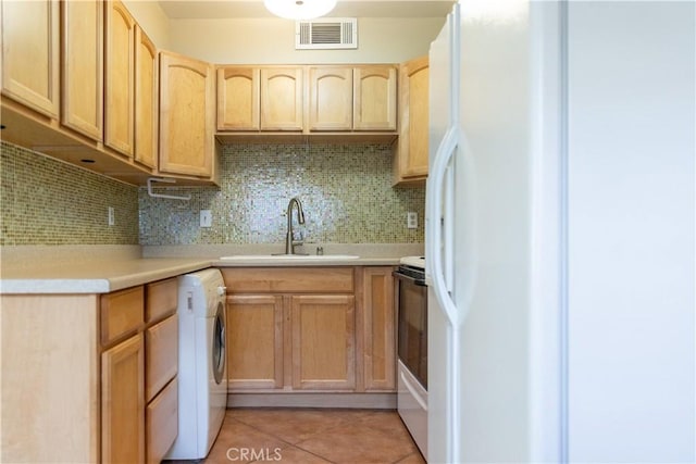 kitchen featuring sink, white refrigerator, backsplash, washer / clothes dryer, and light tile patterned floors