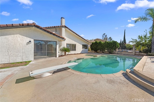 view of pool with a patio area and a diving board