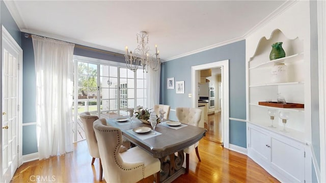 dining room featuring light hardwood / wood-style floors, ornamental molding, and a notable chandelier